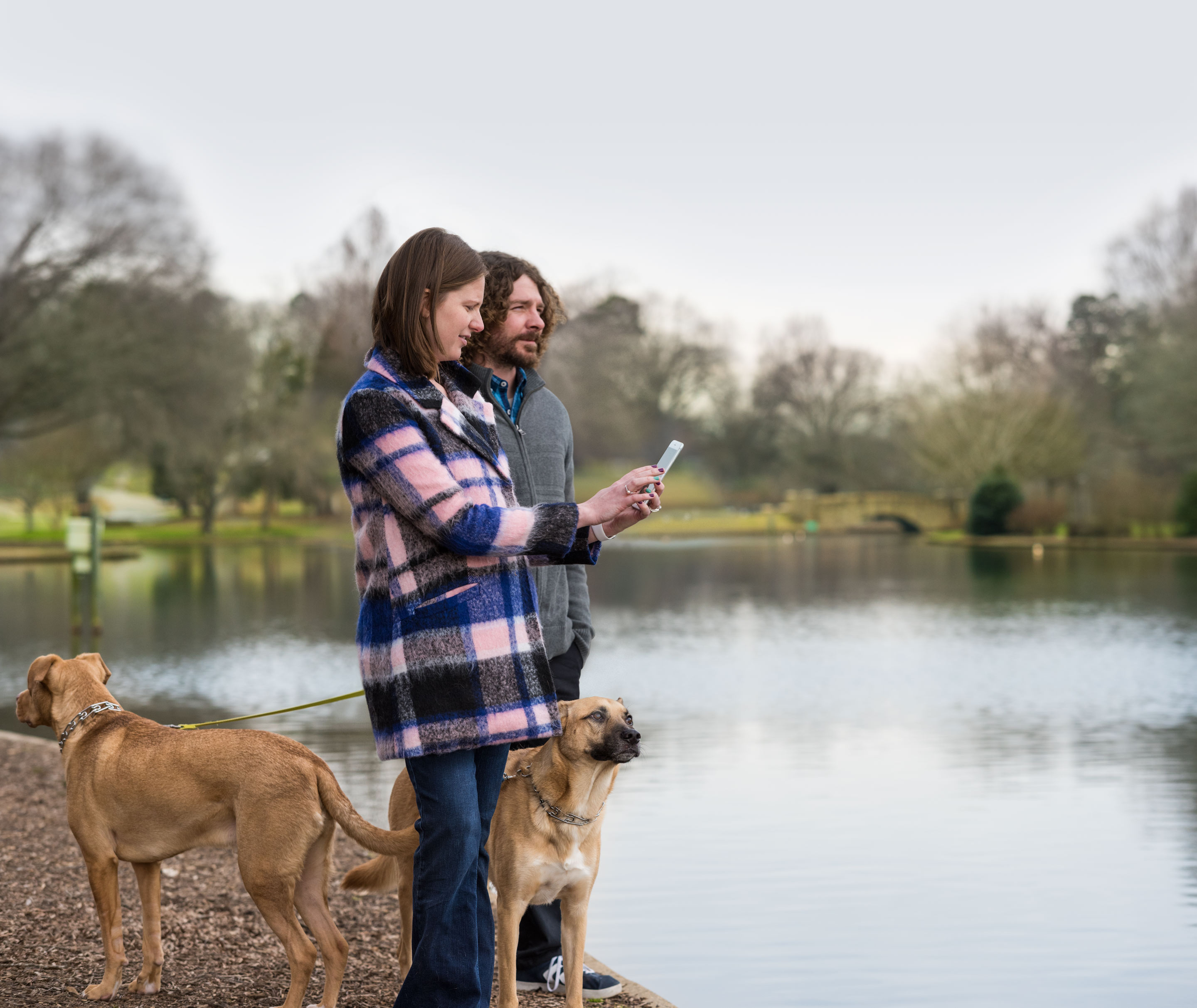 Casal em pé com um cachorro perto de um lago (CareKit)
