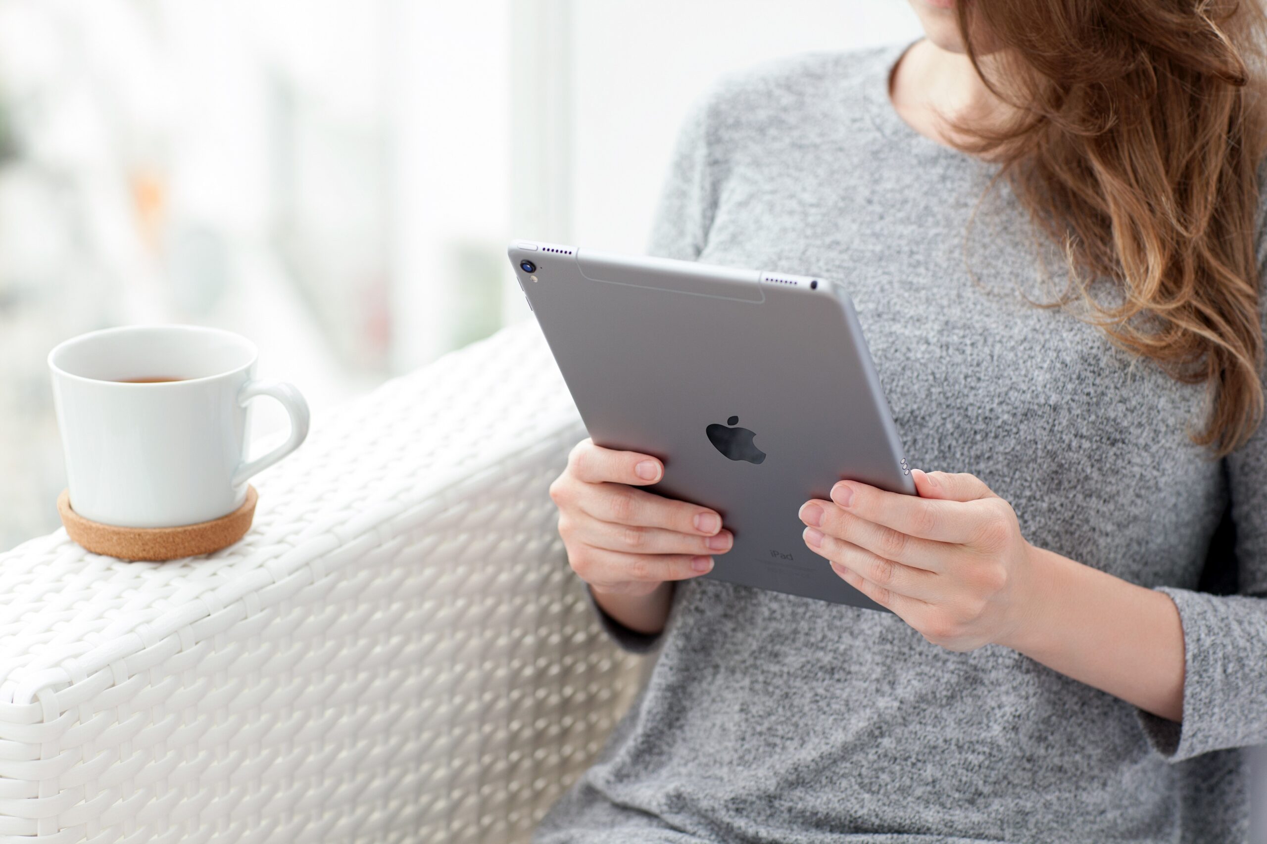 Mulher usando iPad com xícara de café ao lado