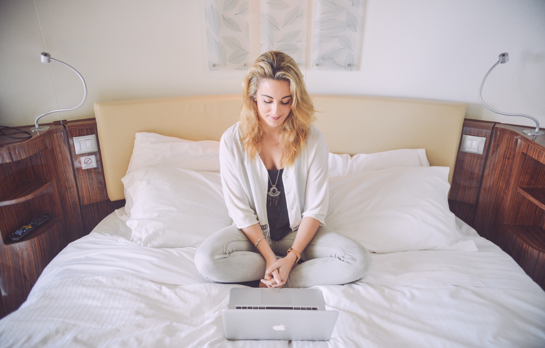 Mulher sentada na cama com um MacBook Pro