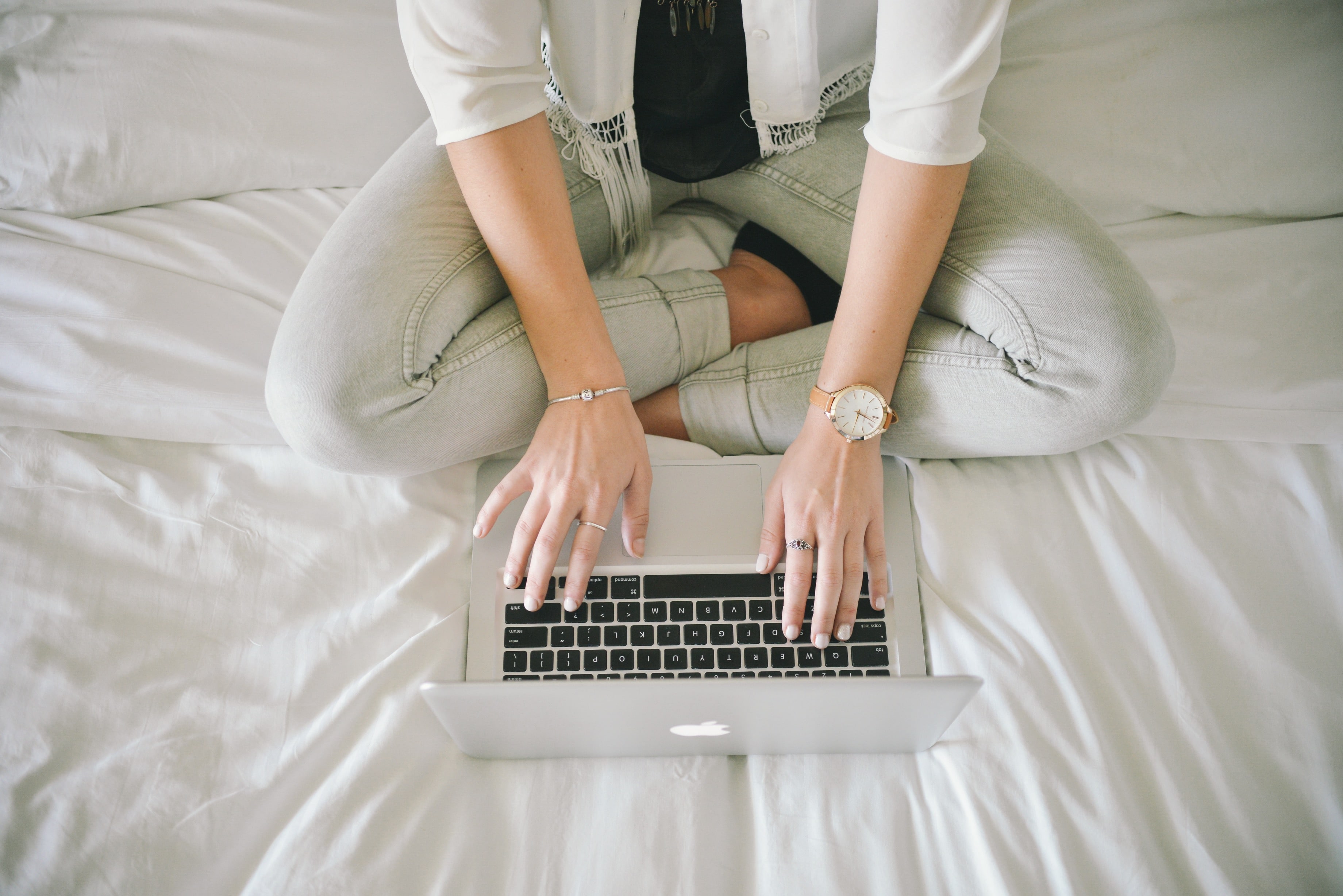 Mulher usando um MacBook Pro em cima da cama