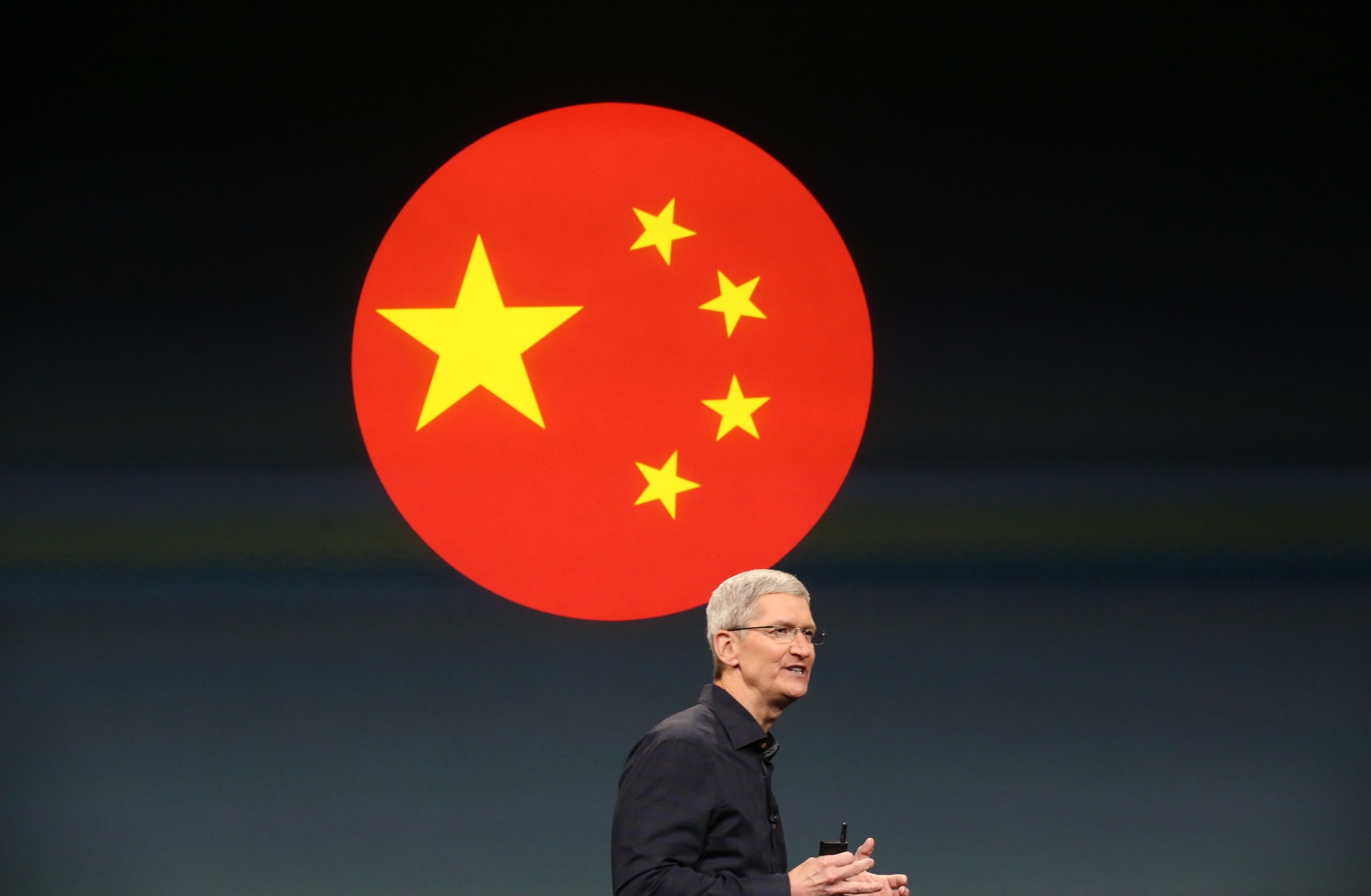 Tim Cook em evento da Apple com a bandeira da China ao fundo