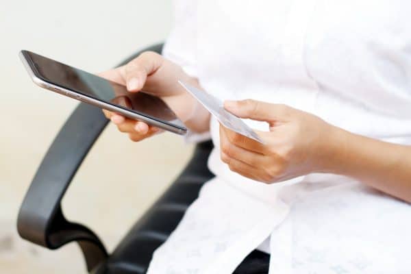 Pessoa segurando um iPhone e um cartão de crédito