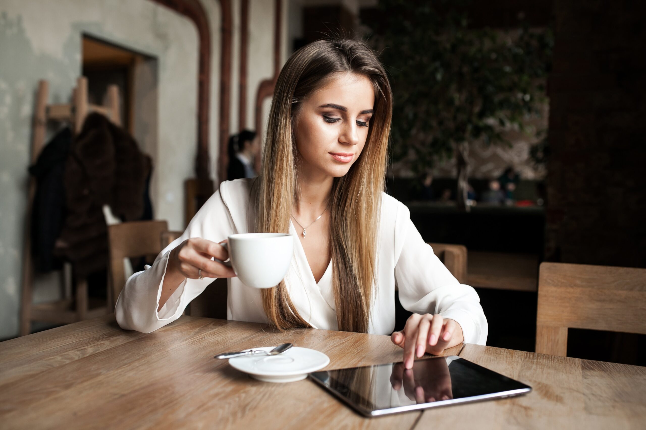Mulher tomando café e lendo em iPad