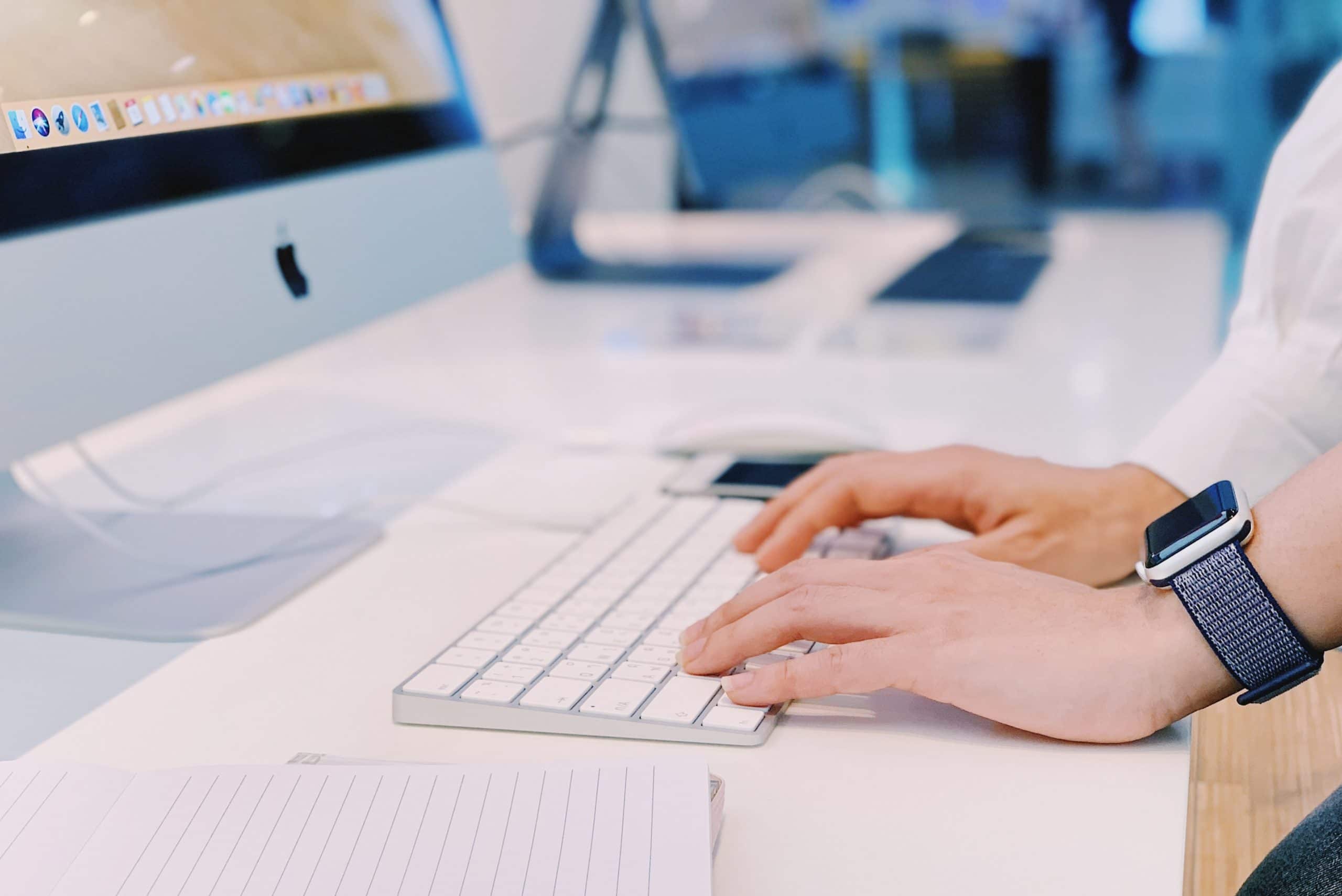 Pessoa digitando em Magic Keyboard conectado a um iMac
