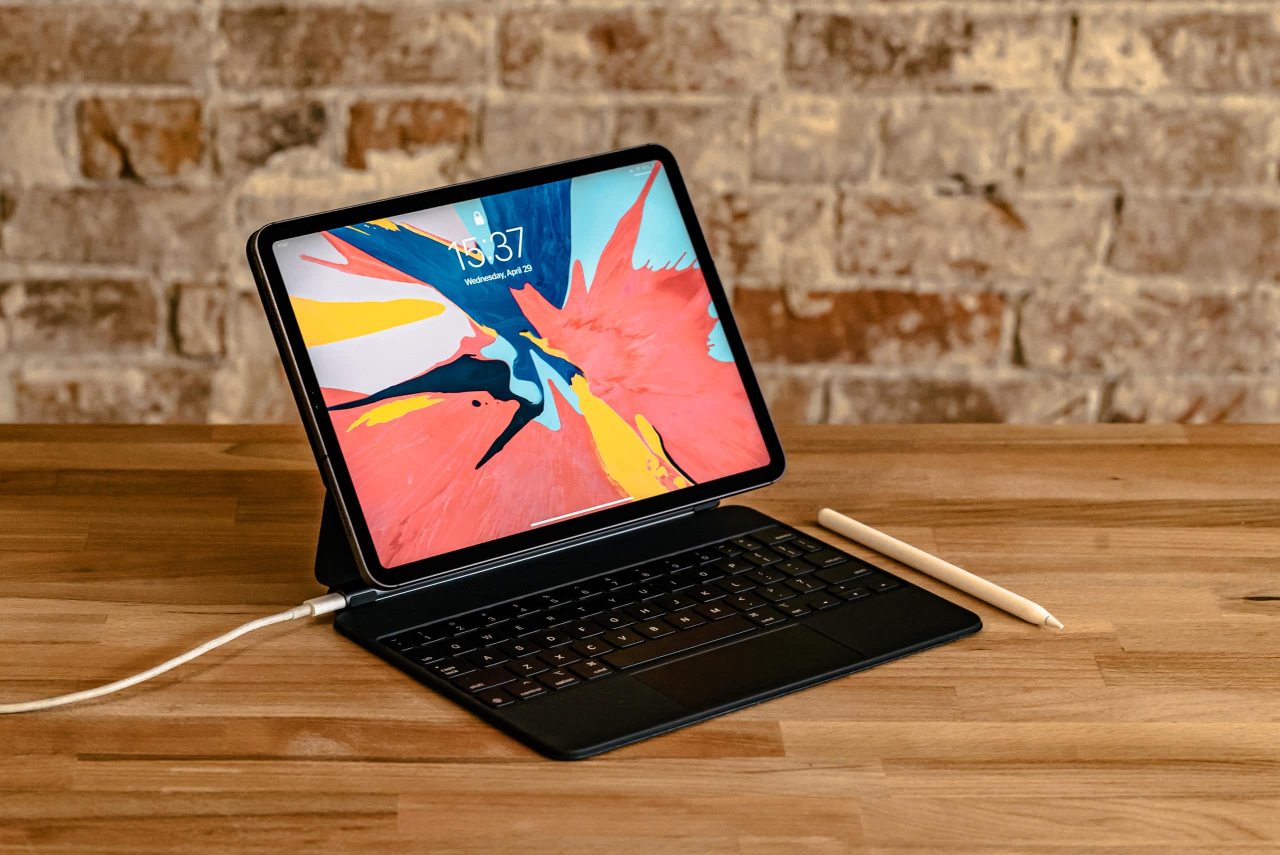 iPad Pro com Magic Keyboard e Apple Pencil sobre mesa de madeira