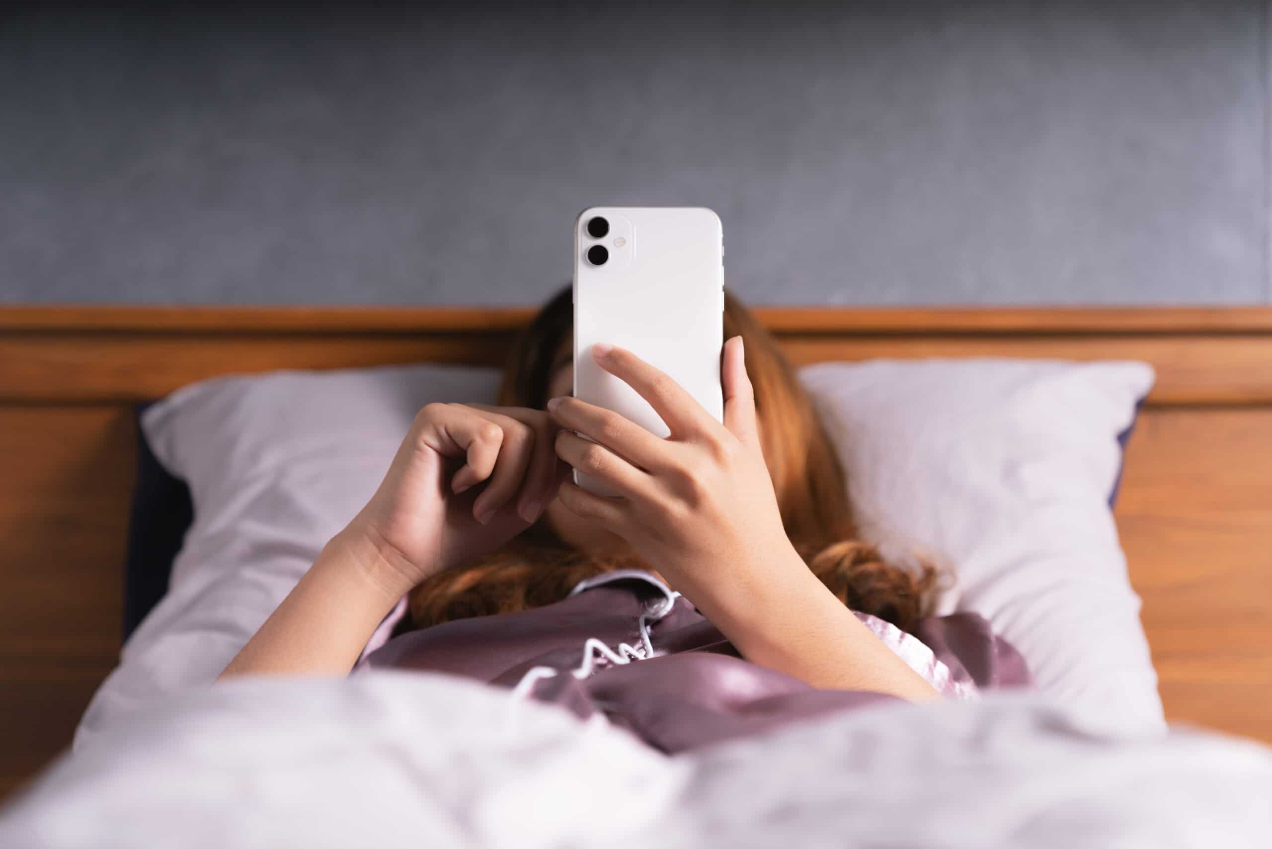 Mulher usando o iPhone na cama