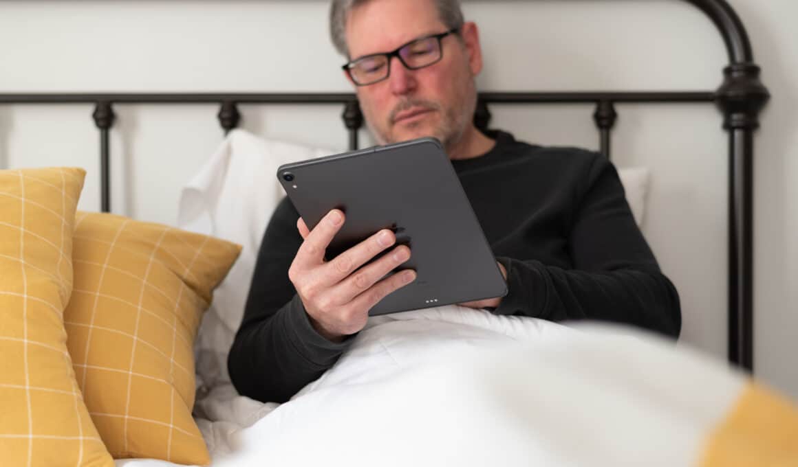 Homem trabalhando em iPad Pro na cama