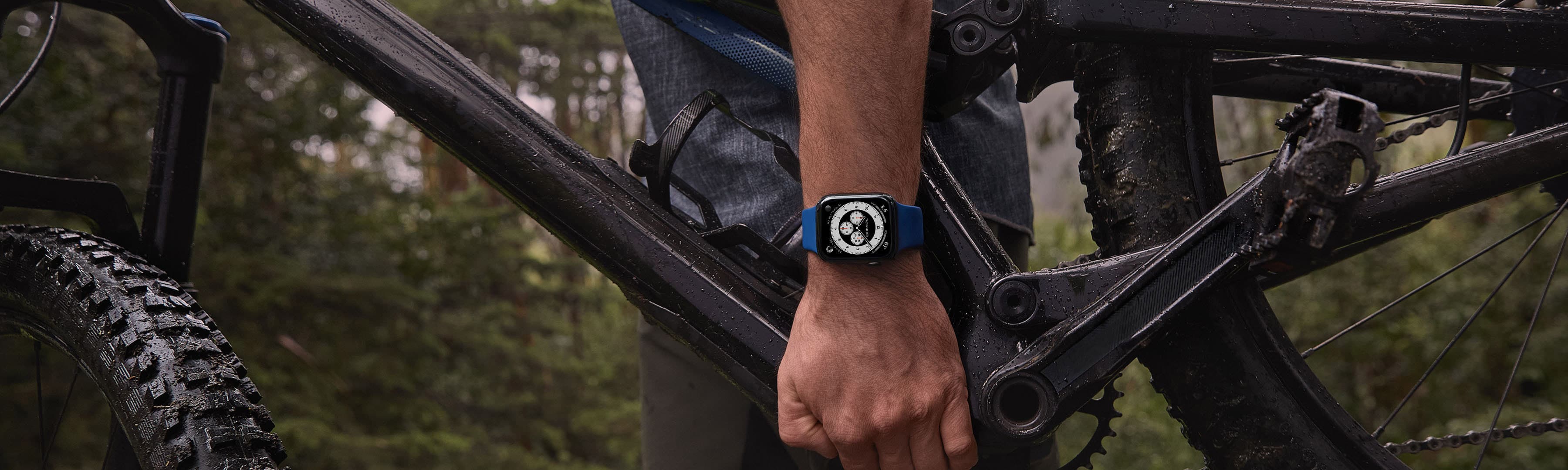 A man holds a bike and an Apple Watch on his wrist