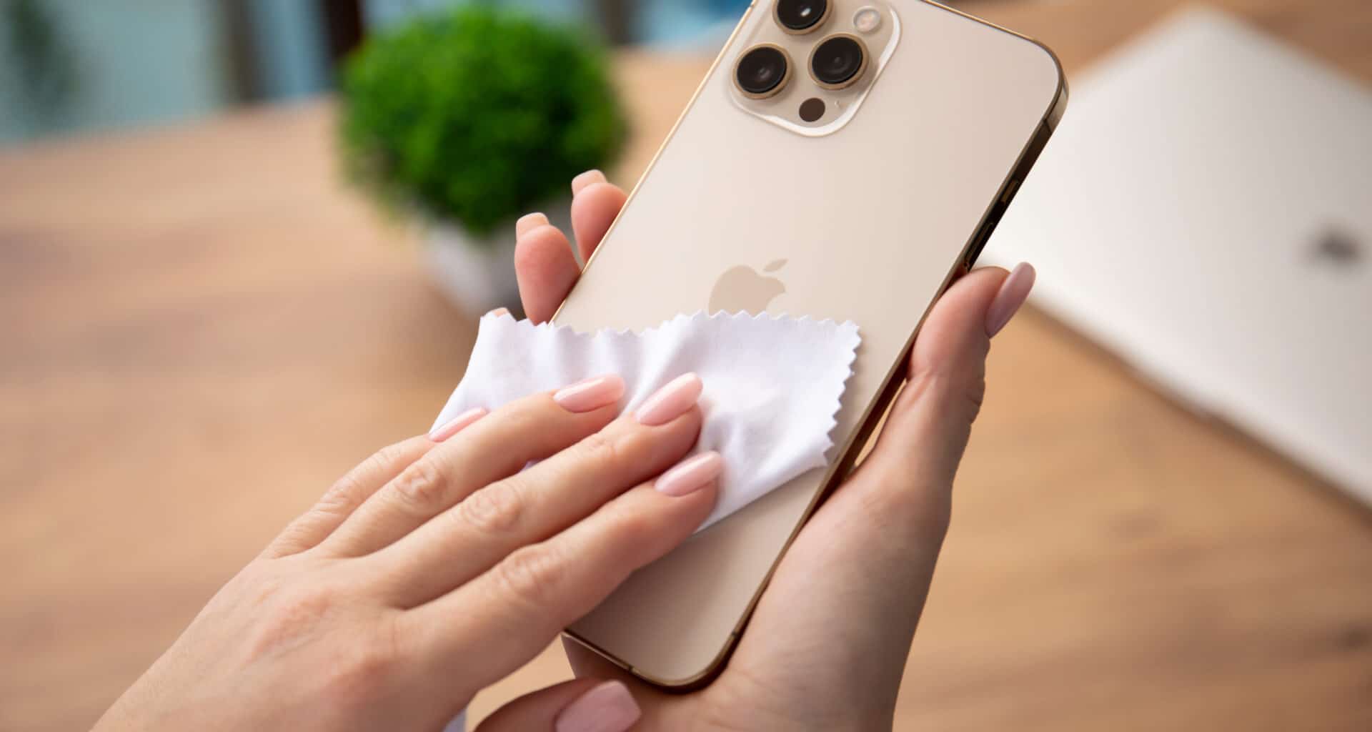 iPhone 12 Pro Max dourado sendo limpo com paninho de microfibra