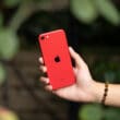 iPhone SE vermelho em mão
