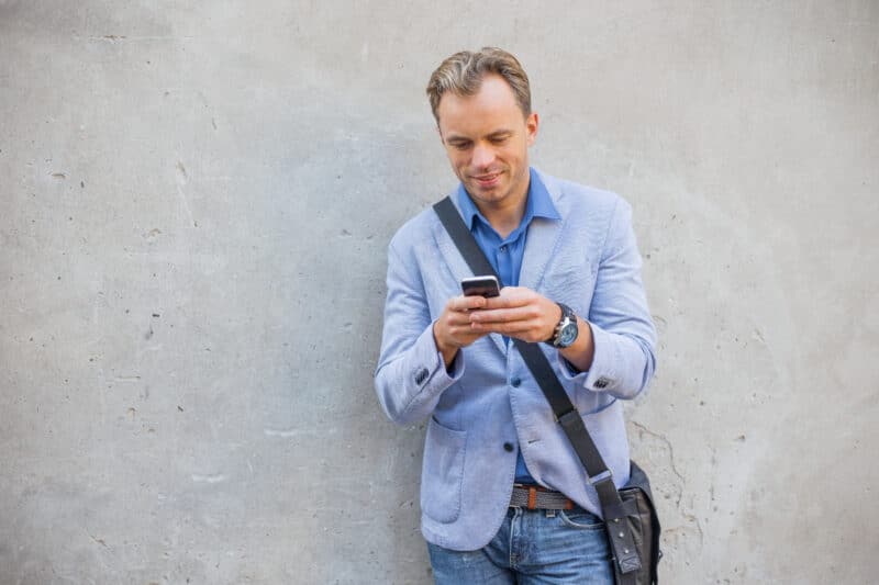 Homem em frente a parede usando iPhone