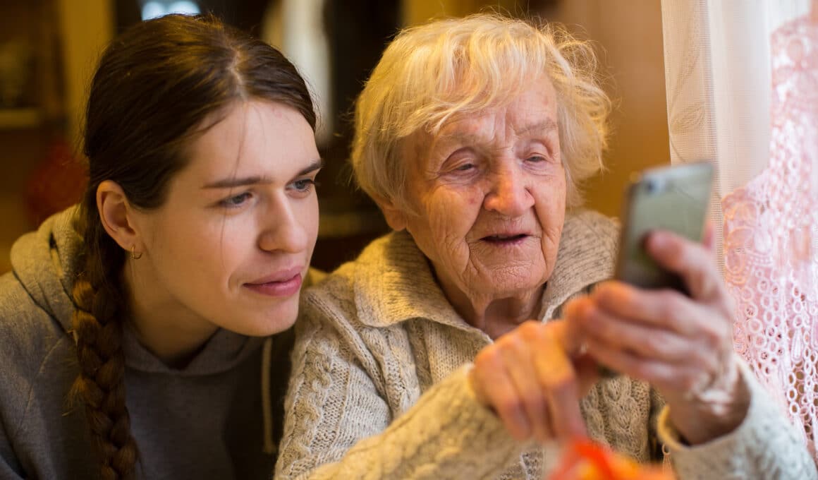 Mulher mais velha segurando um smartphone com uma mais nova ao lado