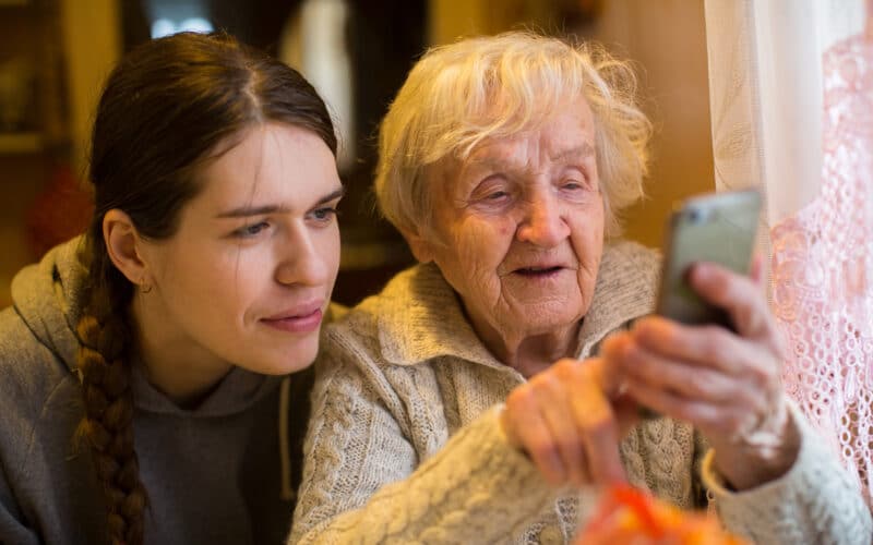 Mulher mais velha segurando um smartphone com uma mais nova ao lado