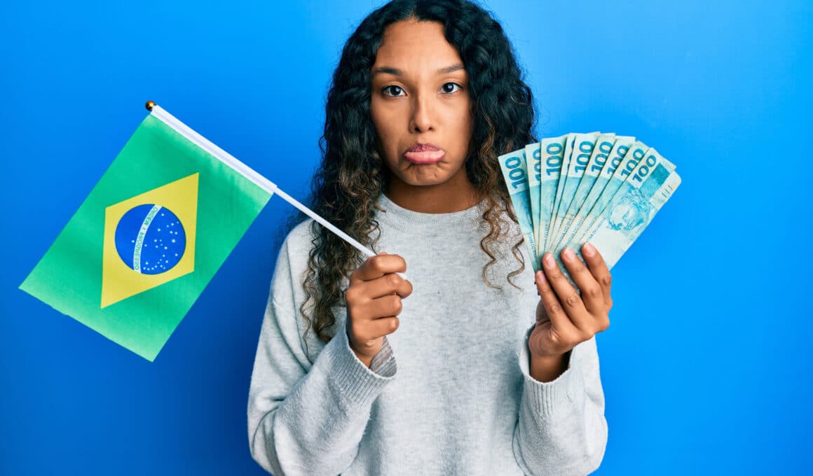 Mulher triste segurando uma bandeira do Brasil e dinheiro