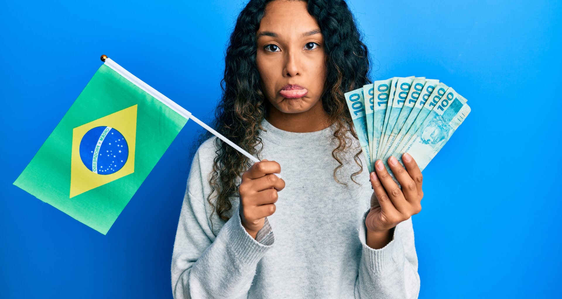 Mulher triste segurando uma bandeira do Brasil e dinheiro