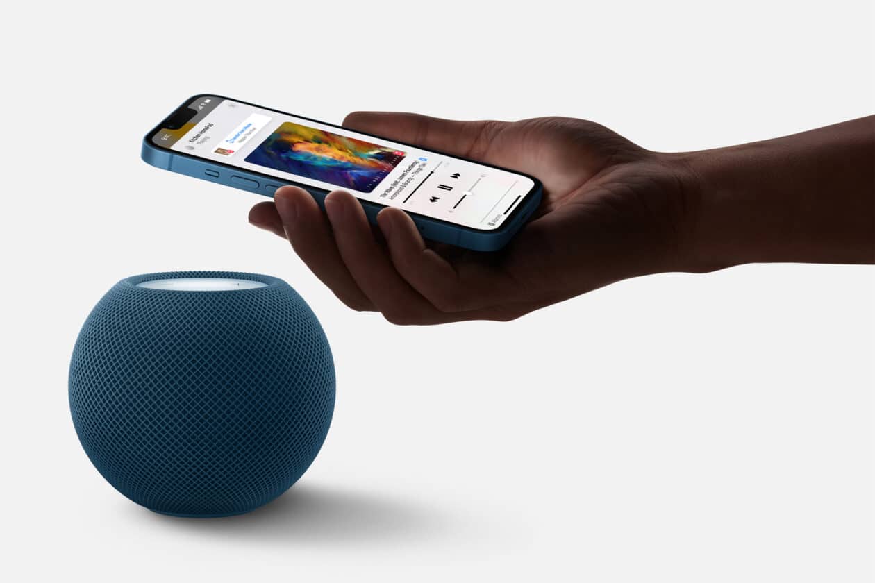 Mão transferindo música de um iPhone para um HomePod mini azul