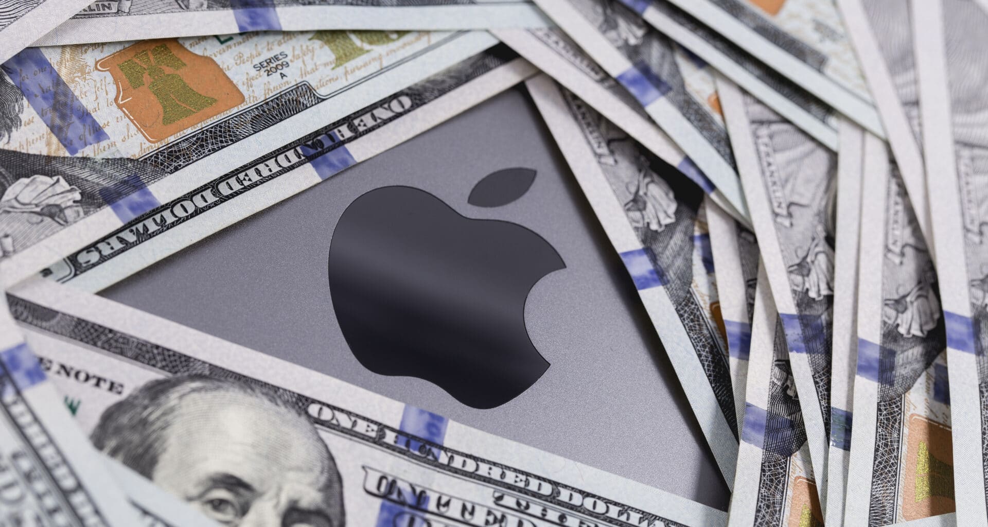 Dinheiro em cima de um MacBook Pro com o logo da Apple