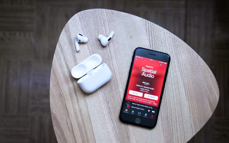 iPhone com Apple Music e fones AirPods Pro ao lado