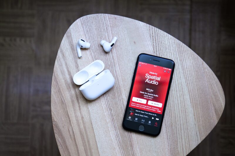 iPhone com Apple Music e fones AirPods Pro ao lado