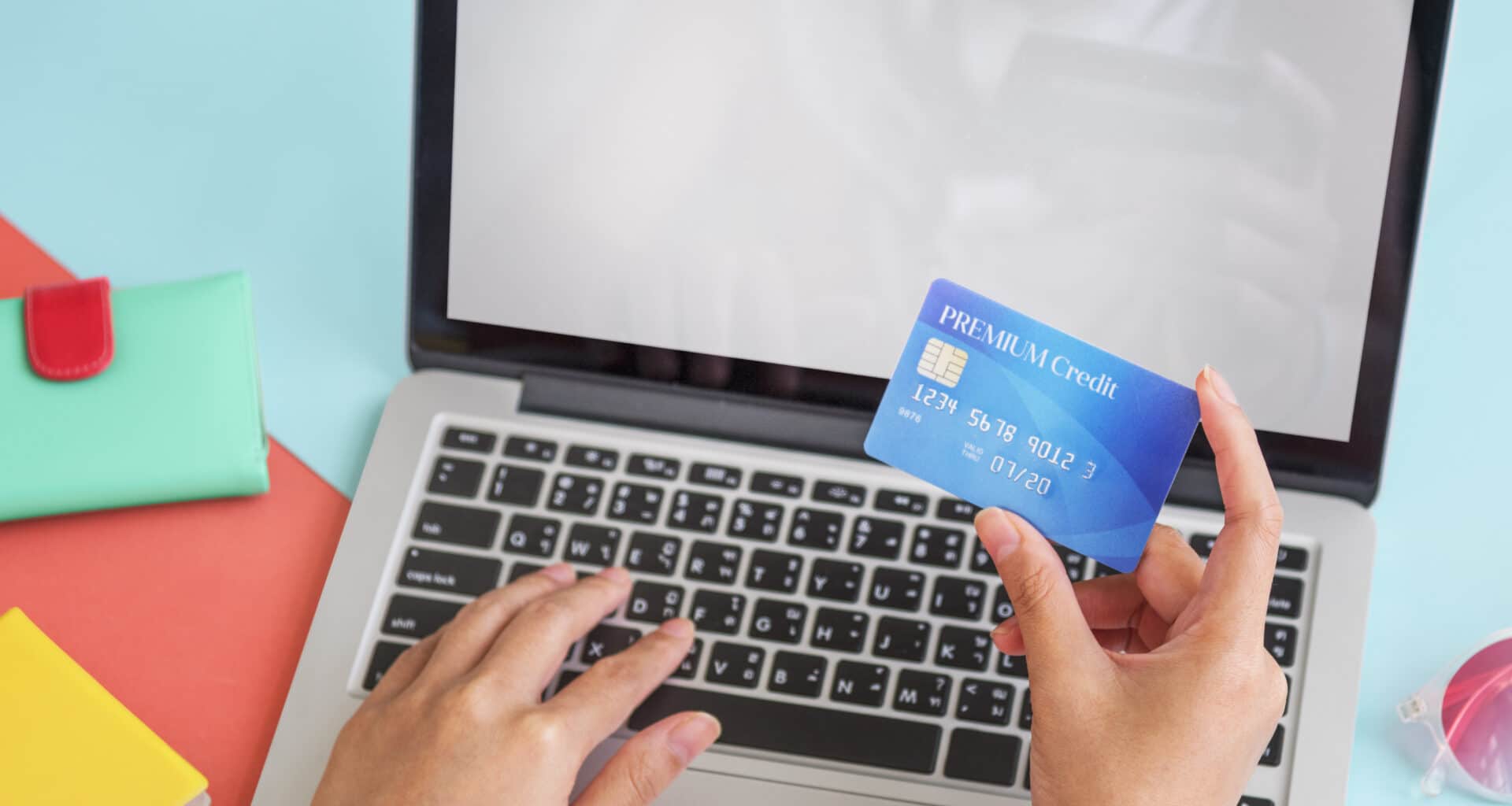 Pessoa segurando um cartão de crédito e preenchendo dados em um Mac