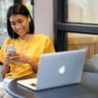 Garota lendo/usando iPhone com MacBook Air ao lado