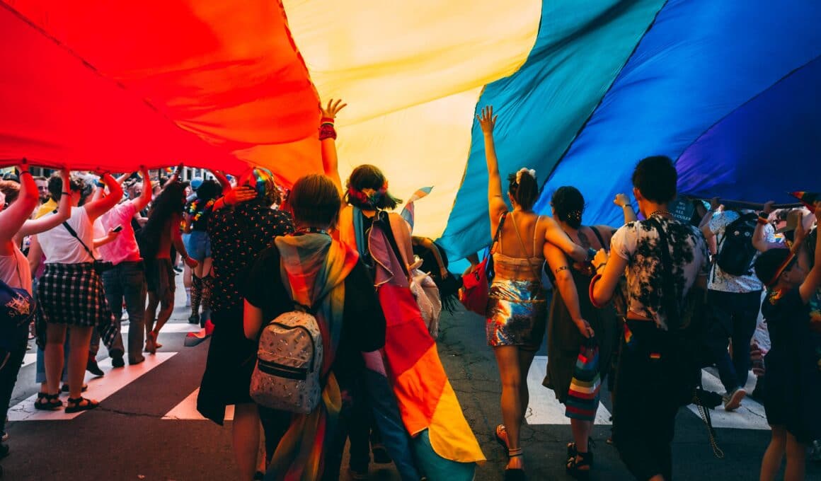 Pessoas embaixo de uma bandeira do arco-íris (LGBTQ+)