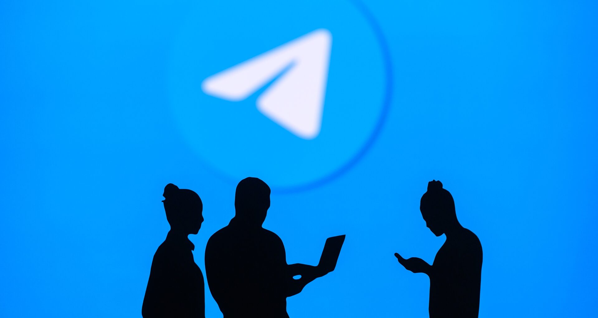 Pessoas em frente a um telão com ícone do Telegram