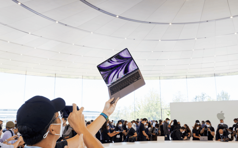 Pessoa segurando o MacBook Air M2 no ar dentro do Steve Jobs Theater do Apple Park, na WWDC22