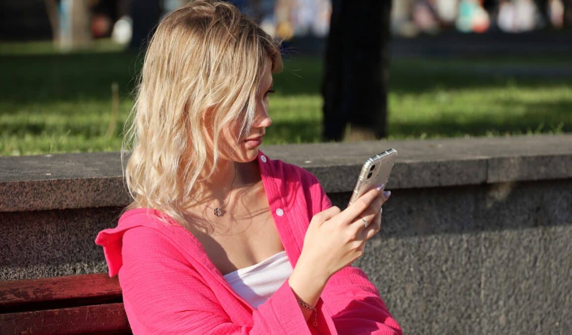 Menina usando iPhone no banco da praça