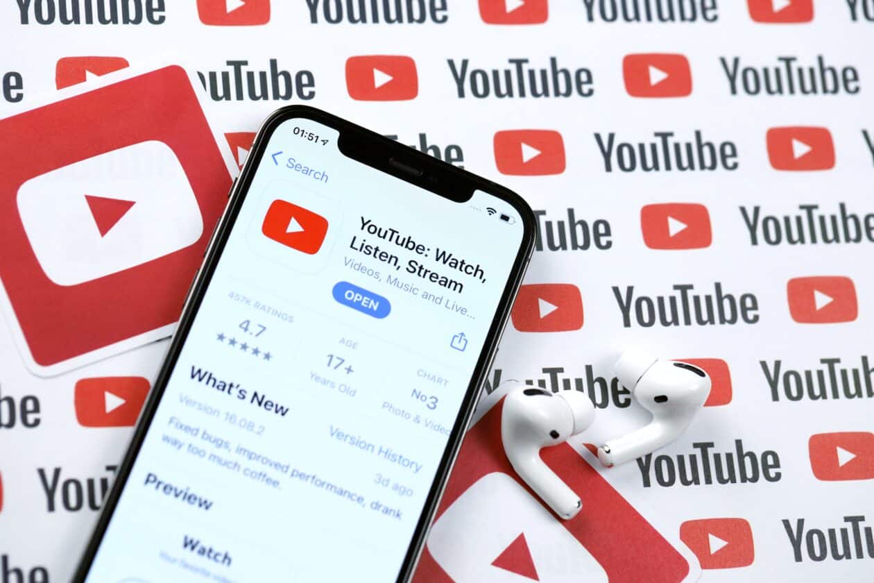 iPhone com app do YouTube em mesa com AirPods Pro ao lado