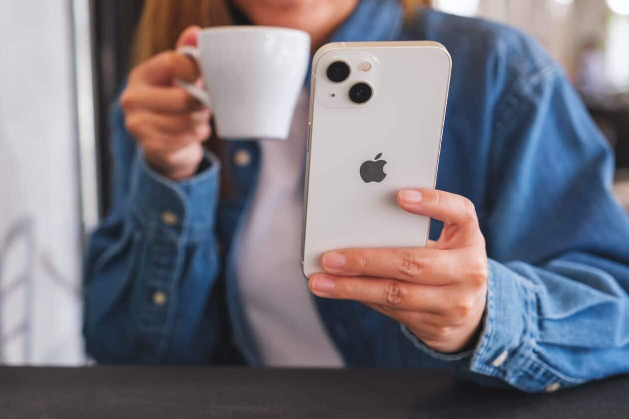 Mulher tomando café e usando o iPhone