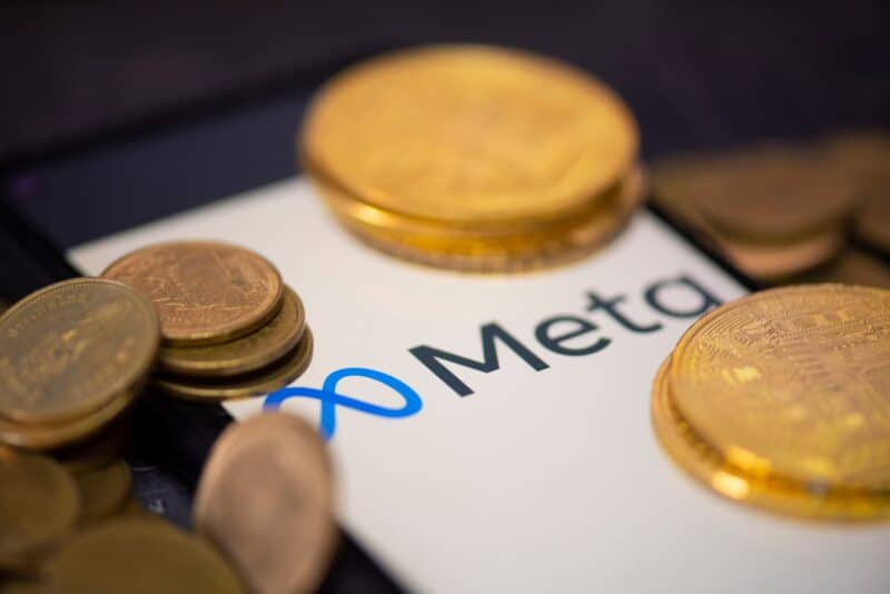 Logo da Meta em smartphone com moedas/dinheiro