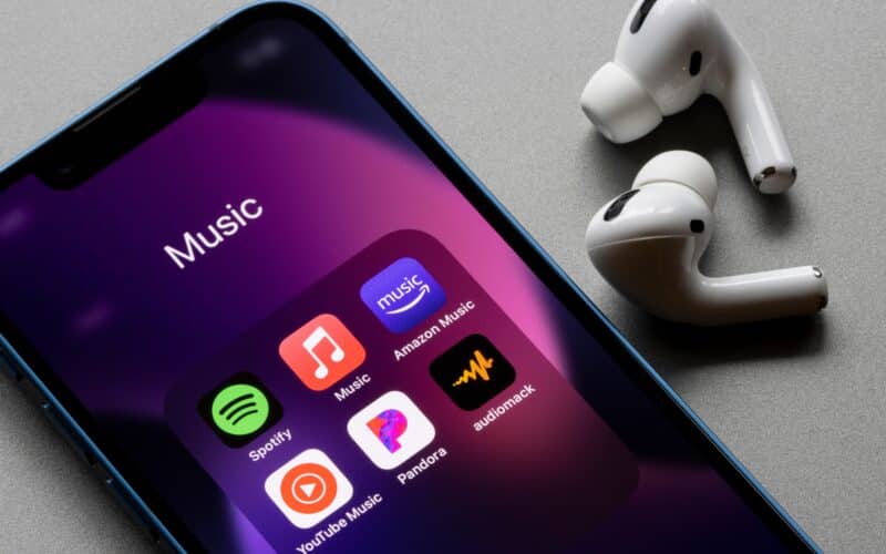 Apps de streaming de músicas num iPhone com AirPods Pro ao lado