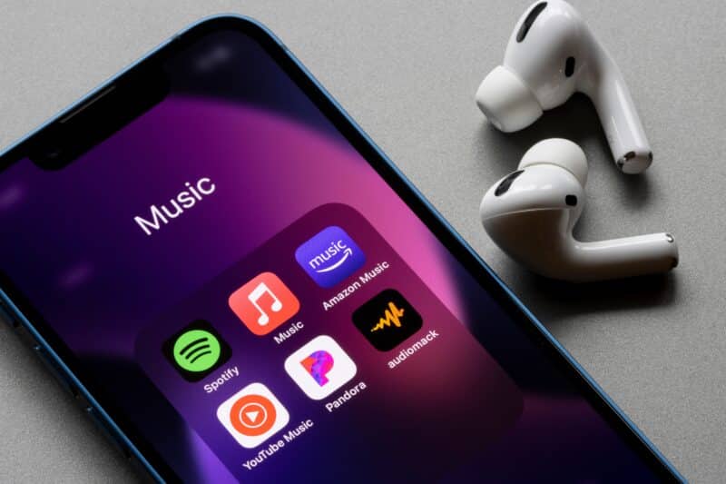Apps de streaming de músicas num iPhone com AirPods Pro ao lado