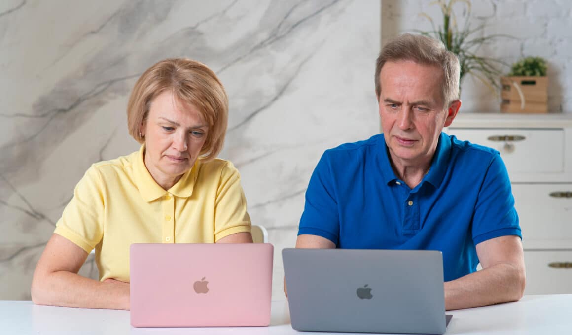 Casal de idosos trabalhando em MacBooks