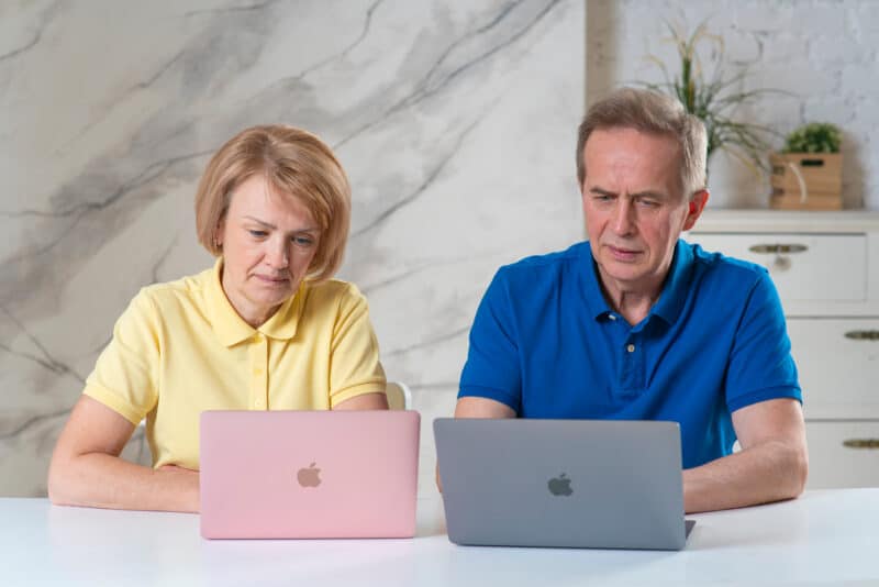 Casal de idosos trabalhando em MacBooks