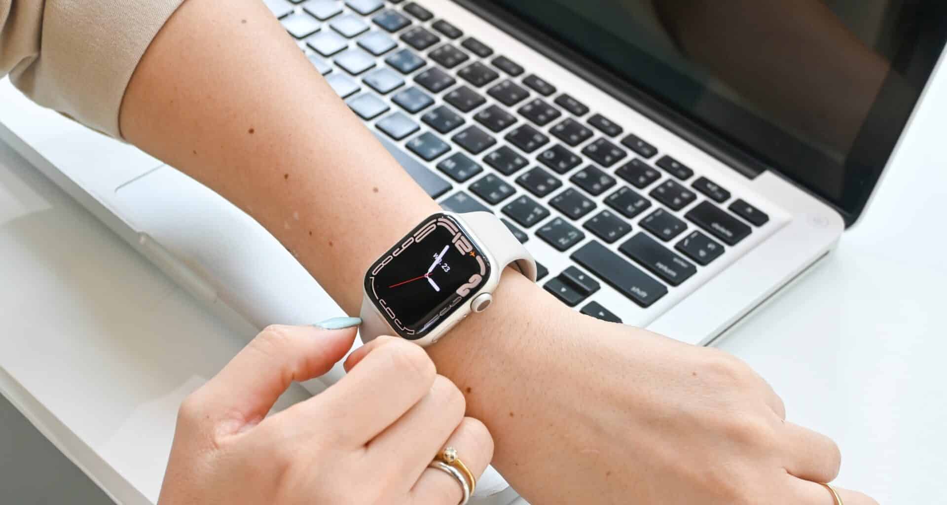 Mulher usando um Apple Watch com um Mac ao fundo