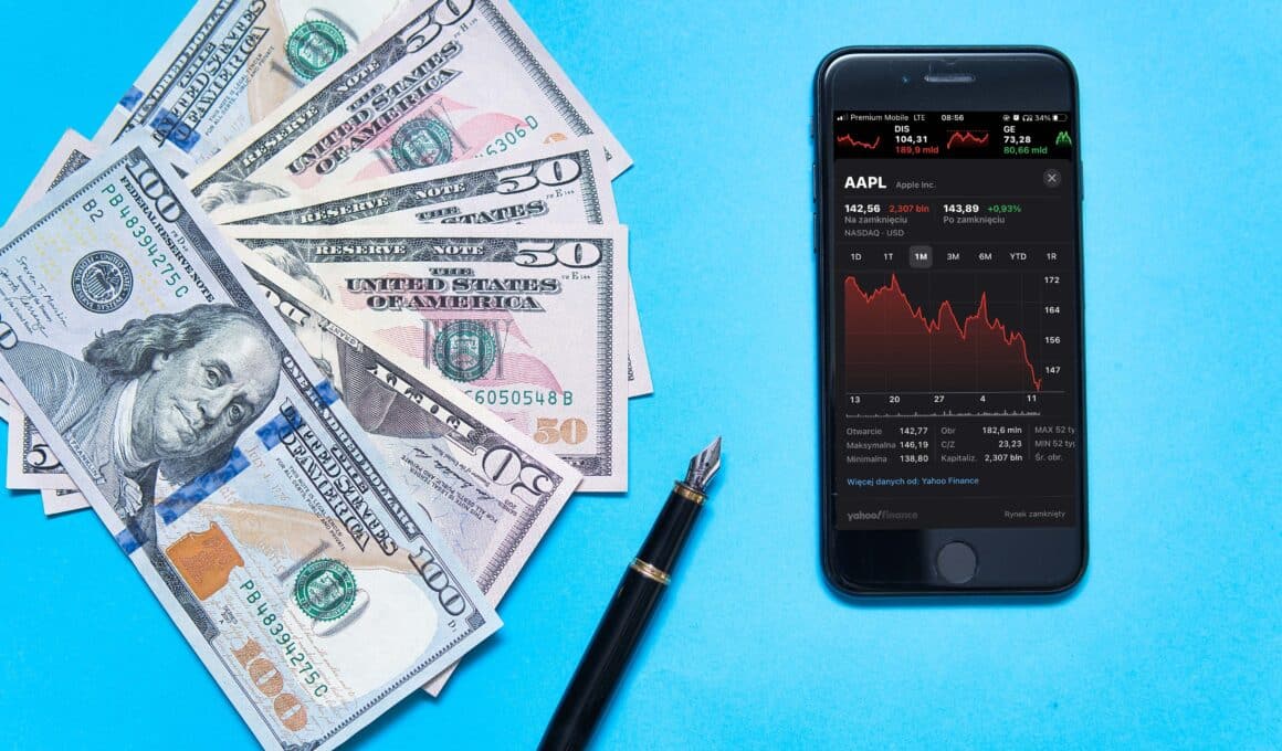 Ações da Apple aparecendo no app Bolsa (no iPhone) com dinheiro e uma caneta ao lado