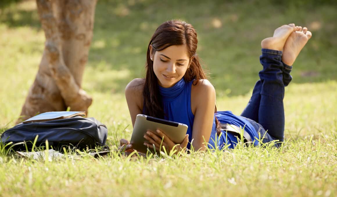 Garota num parque lendo num iPad