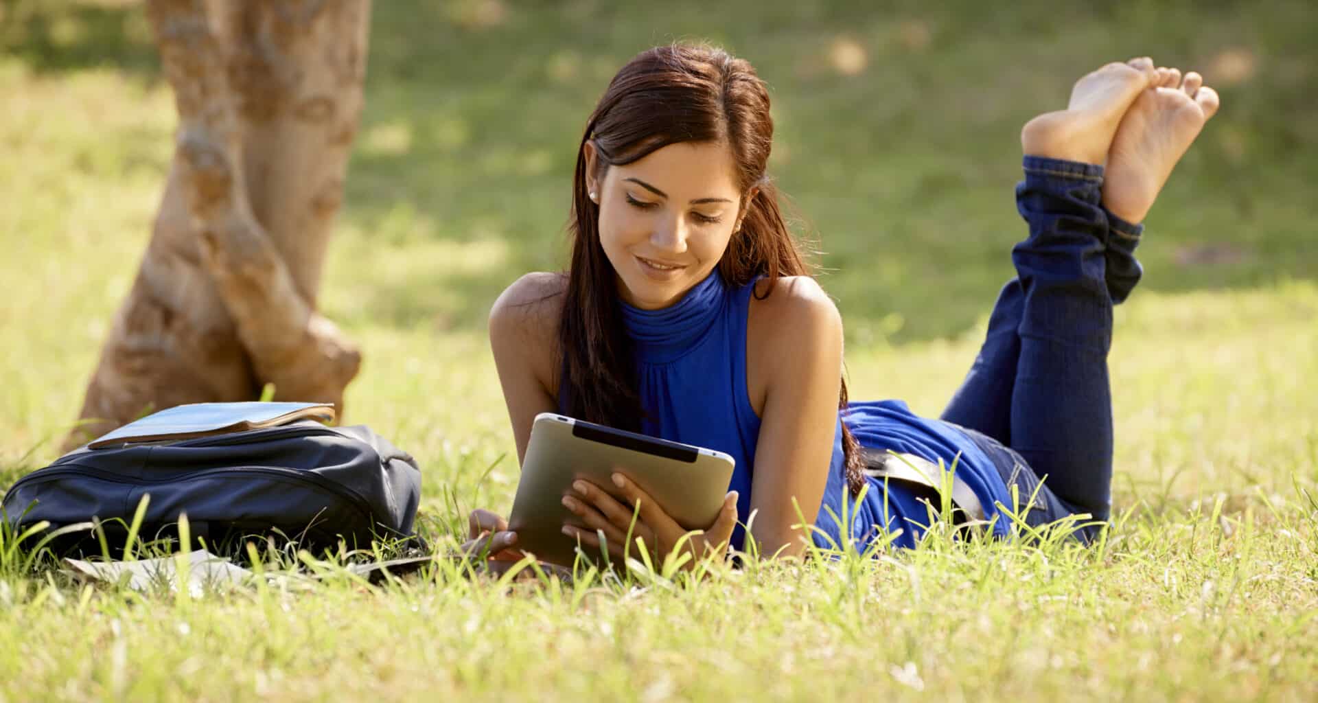 Garota num parque lendo num iPad