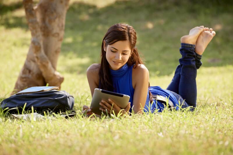Garota num parque lendo num iPad