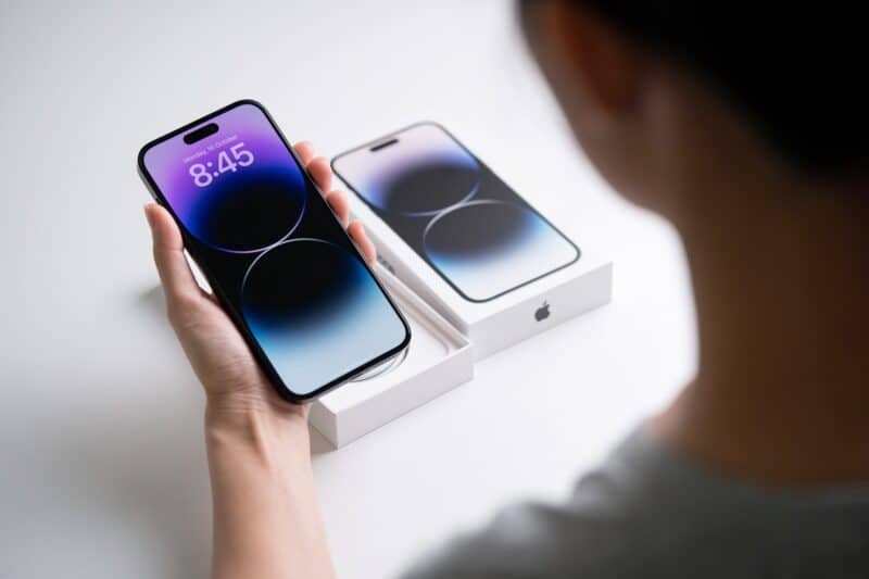 iPhone 14 Pro Max na mão de uma pessoa com a caixa ao fundo
