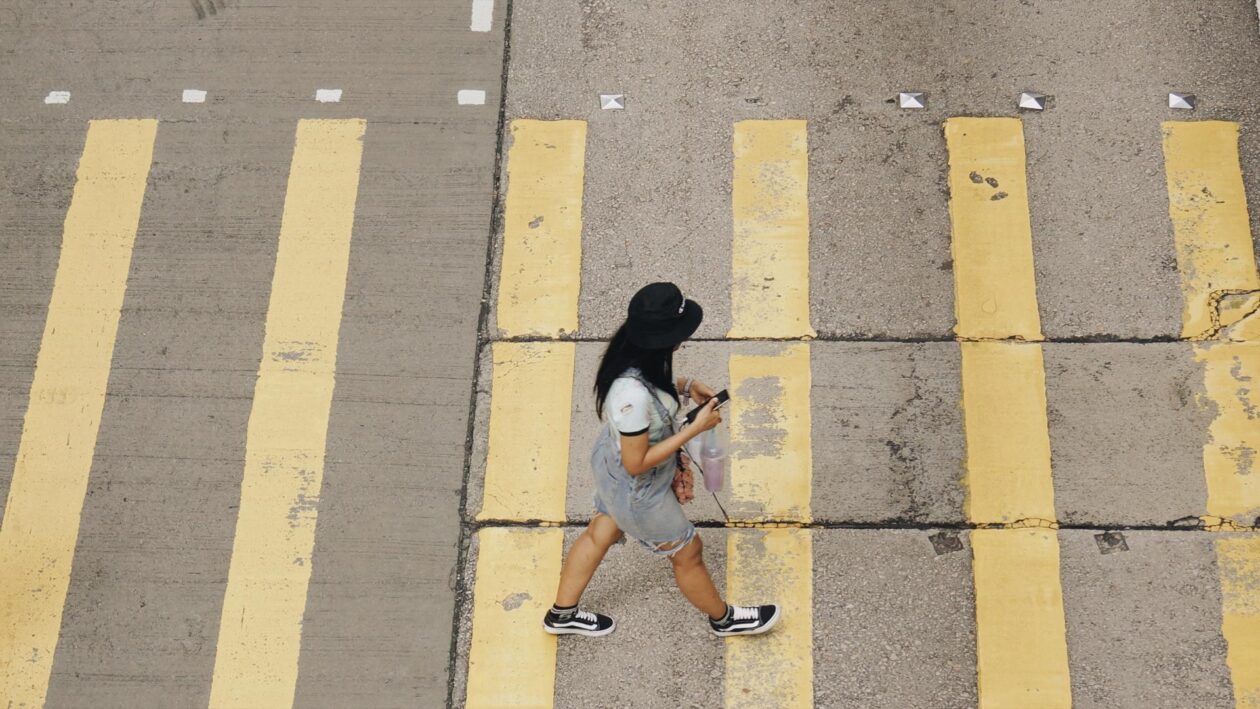 Mulher atravessando a rua com smartphone na mão