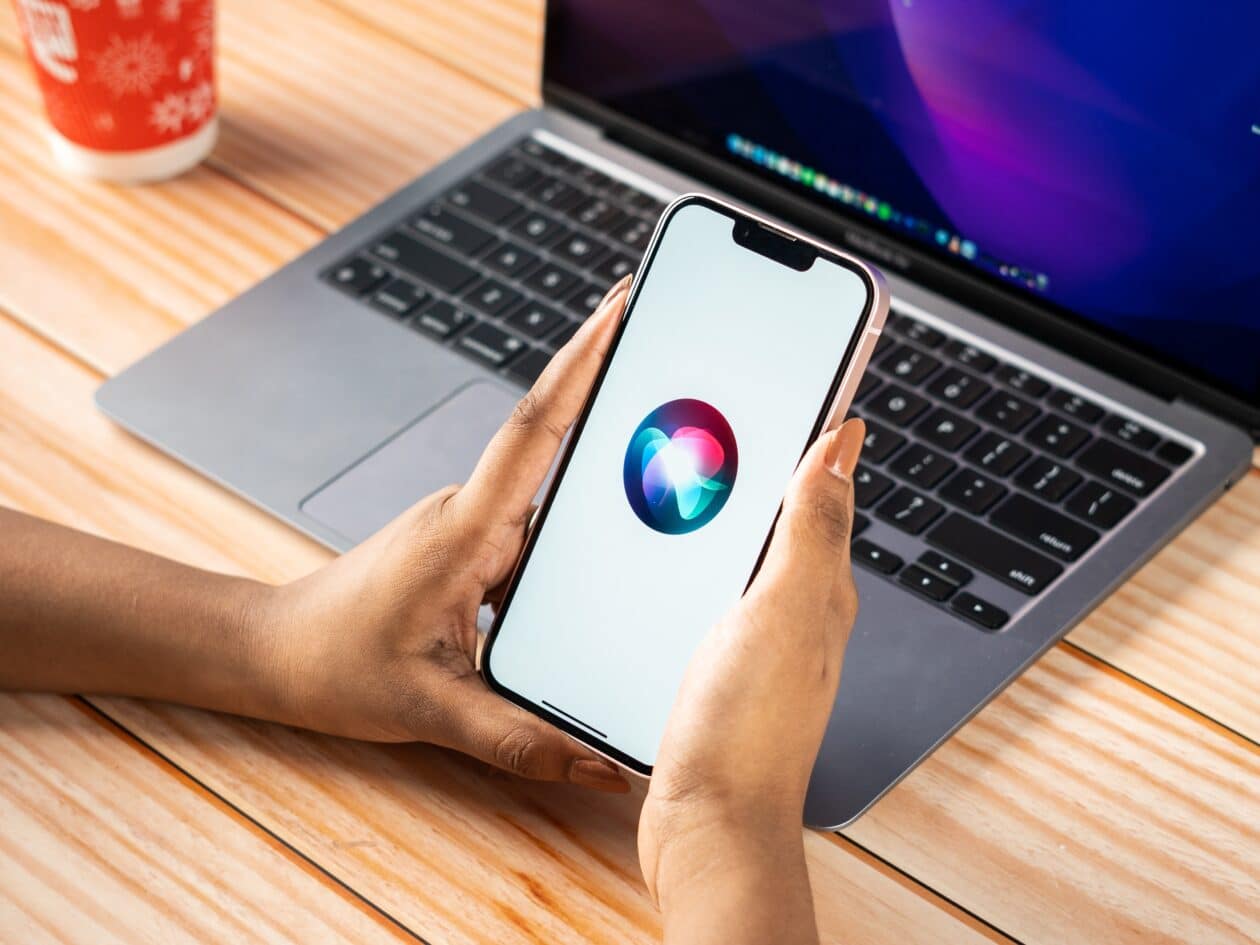 Siri no iPhone com um Mac ao fundo
