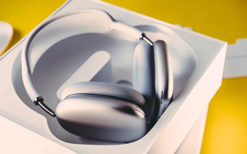 AirPods Max na caixa aberta sobre um fundo amarelo