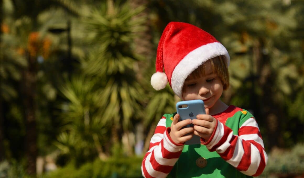 Garoto com gorro de Papai Noel usando iPhone