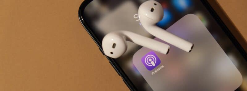 AirPods sobre iPhone com o app Apple Podcasts visível