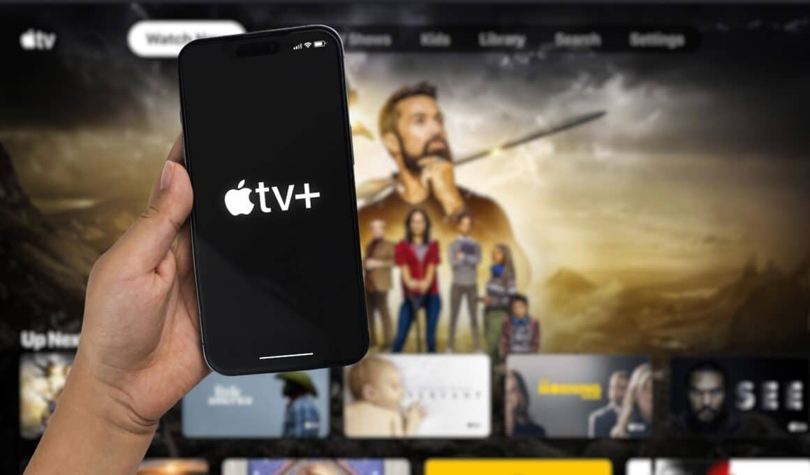 iPhone 14 Pro com o logo do Apple TV+ em frente a uma Apple TV
