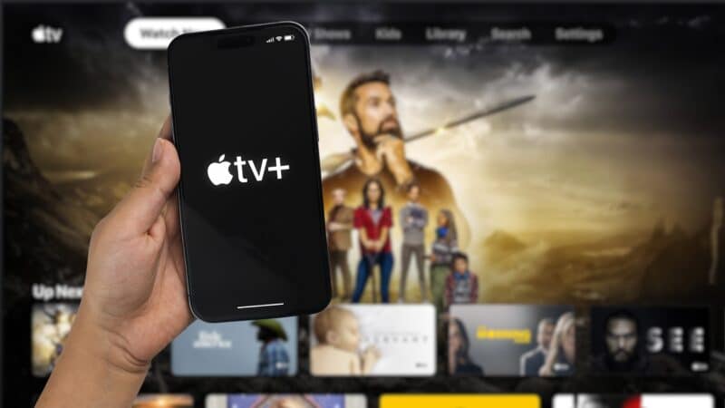 iPhone 14 Pro com o logo do Apple TV+ em frente a uma Apple TV