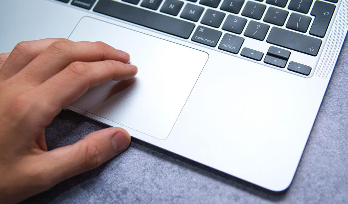Mão de homem sobre trackpad/teclado de um MacBook Pro